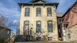 A two-story brick building with a central entrance, large windows, and a small porch. - Cream City Victorian Parking AC Patio Walkable (Milwaukee)
