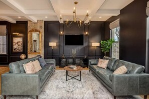 Relax in this stylish living room with a large flat-screen TV, comfortable sofas, and a beautiful chandelier.
