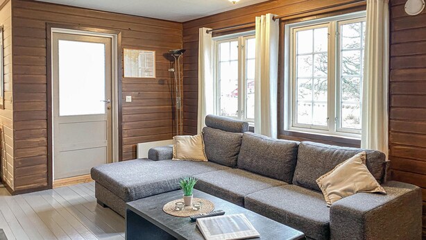 A cozy room with a grey sofa, a small coffee table, and a window with curtains. - Nice home in Offersøy with sauna (Offersøy)