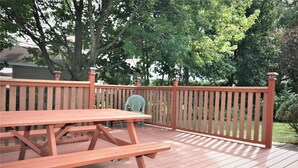 A wooden deck with picnic tables and chairs, surrounded by a wooden fence. - Bright, clean, comfortable, well maintained home (Ottawa)