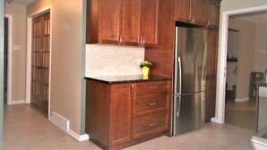 A kitchen with wooden cabinets, a stainless steel refrigerator, and a tiled backsplash. - Bright, clean, comfortable, well maintained home (Ottawa)