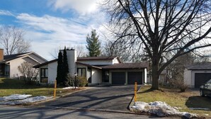A residential driveway leading to a house with a garage, a large tree, and snow patches on the lawn. - Bright, clean, comfortable, well maintained home (Ottawa)