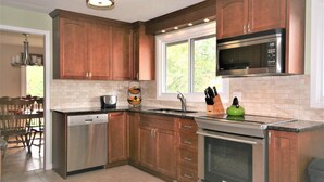 A modern kitchen with wooden cabinets, stainless steel appliances, and a window providing natural light. - Bright, clean, comfortable, well maintained home (Ottawa)