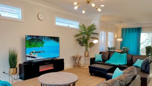 A modern living room with a flat-screen TV, a large potted plant, a black leather sofa, and a wooden coffee table. - Million dollar villa · Beachfront neighborhood · Free cruise · Resort amenities (Destin)
