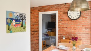 A dining area with a brick wall, a clock, and a table set for four. - 2 bedroom accommodation in Swanwick (Swanwick)