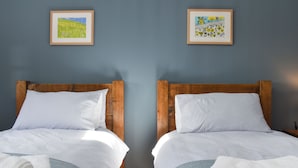 Two twin beds with wooden headboards, white and gray striped bedding, and a blue wall with two framed pictures. - 2 bedroom accommodation in Swanwick (Swanwick)