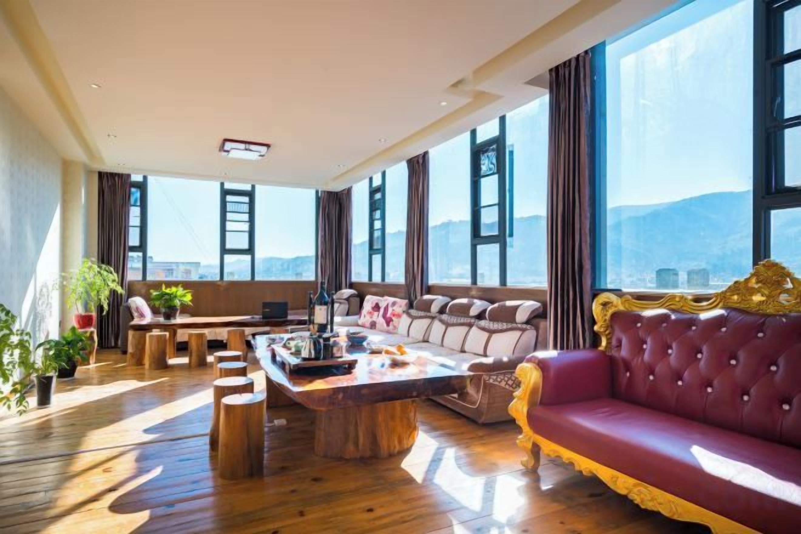 A spacious living room with a large window, a red sofa, and a wooden coffee table.