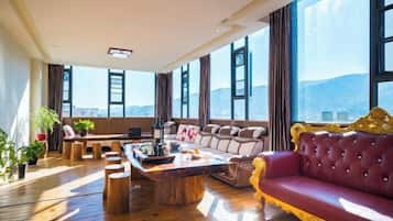 A spacious living room with a large window, a red sofa, and a wooden coffee table.