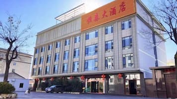 A multi-story building with a flat facade, large windows, and a prominent entrance with a red awning.