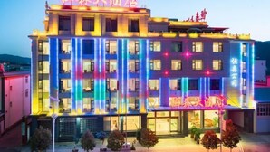 Un hotel con fachada moderna, varios pisos y señalización iluminada.