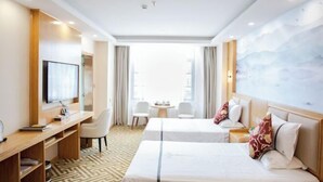 Habitación de hotel con dos camas, un escritorio, un televisor y vista a la ciudad.