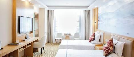 A hotel room with two beds, a desk, a TV, and a view of the city.