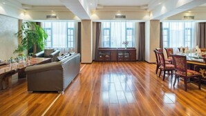 Una habitación amplia con piso de madera, un sofá, una mesa de comedor con sillas y un armario.
