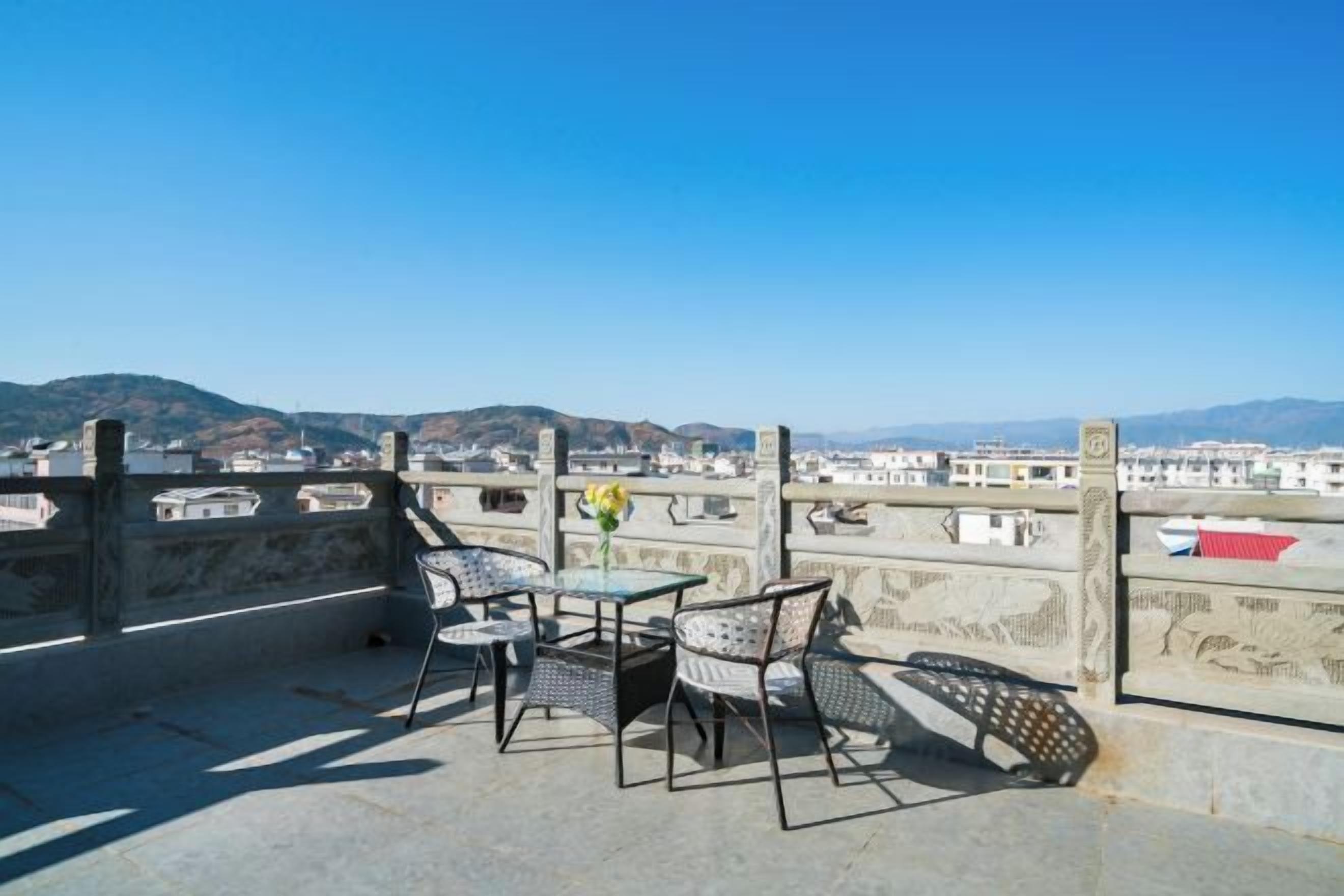 Una terraza con mesa y sillas, con vistas a un paisaje urbano que incluye edificios y colinas.