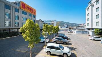 Un parking avec plusieurs voitures, un bâtiment portant une enseigne et un ciel dégagé.