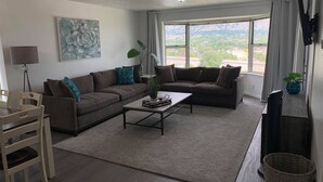 Een woonkamer met een bank, salontafel en een eethoek met stoelen.