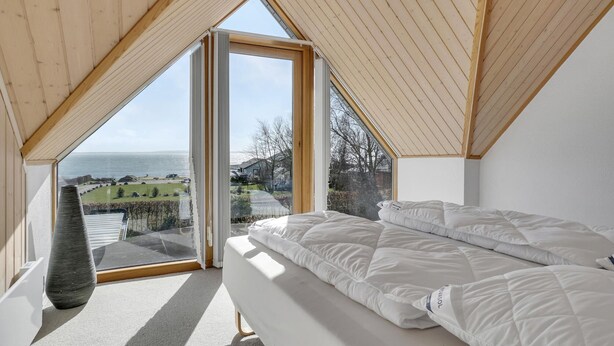 A bedroom with a large window, a bed, and a view of the sea. - Gorgeous home in øster assels (Øster Assels)