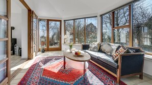 A spacious room with large windows, a sofa, a round table, and a patterned rug. - Gorgeous home in øster assels (Øster Assels)