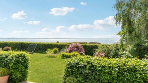 A well-maintained garden with a lawn, various shrubs, and a view of the sea. - Gorgeous home in øster assels (Øster Assels)