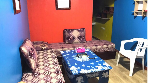A room with a sofa, a small table, and a white chair. There are patterned cushions on the sofa. - Furnished studio (El Ouatia)