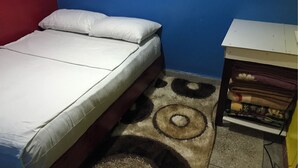 A bed with white bedding, a blue wall, and a patterned rug. - Furnished studio (El Ouatia)