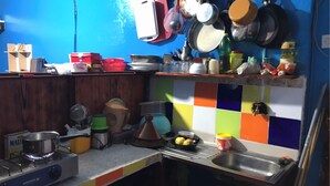 A kitchen with a gas stove, various pots and pans, a sink, and a colorful backsplash. - Furnished studio (El Ouatia)