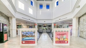 En rymlig entréhall med en pool, ett spelhall och skyltar som visar var toaletterna finns.