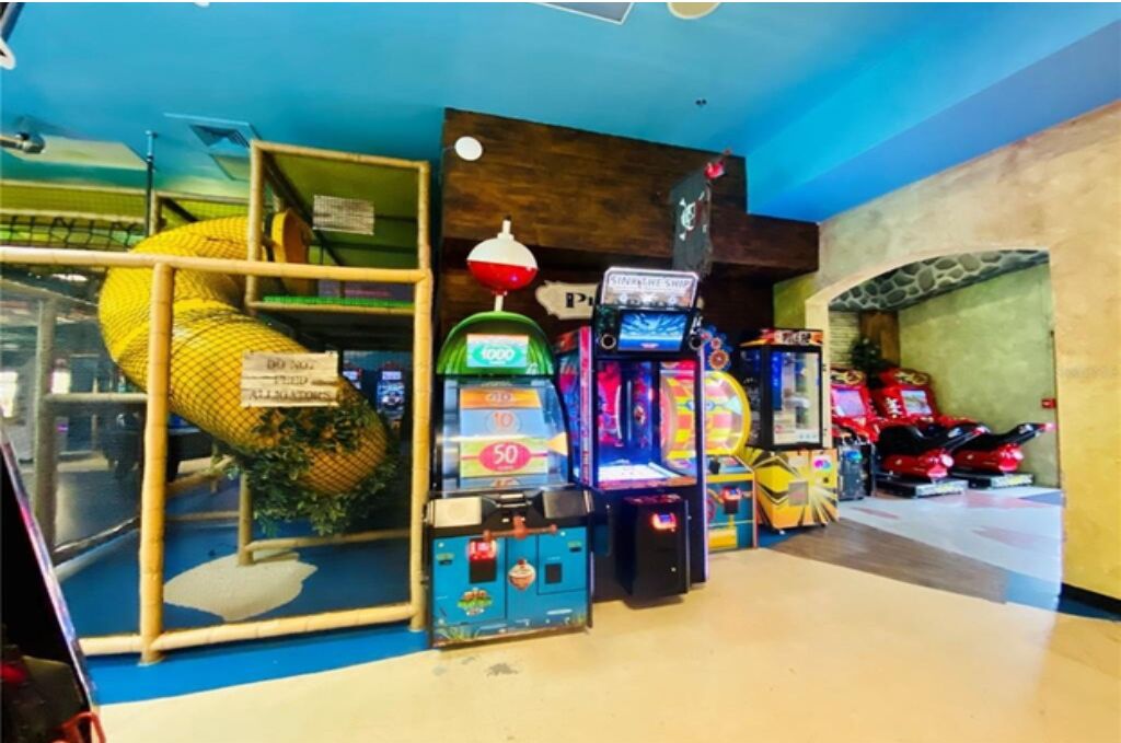 An indoor arcade with various gaming machines, including a pinball machine and a racing game.