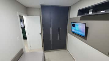 Una habitación con armario, televisor en la pared y puerta que da a otra estancia.