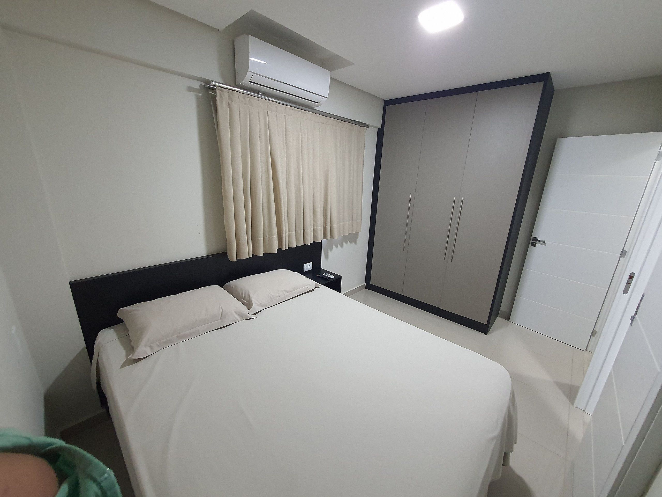 Quarto de hotel com cama, ar condicionado, guarda-roupa e porta.