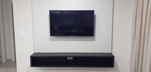 Un televisor de pantalla plana montado en la pared sobre un mueble negro para entretenimiento.