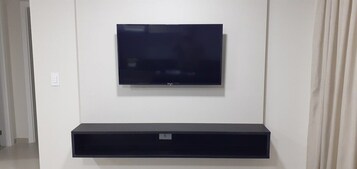 Un televisor de pantalla plana montado en la pared sobre un mueble negro para entretenimiento.