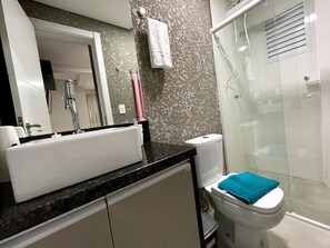 Un baño con lavamanos, espejo, inodoro y ducha.