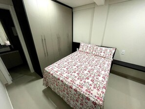 Un dormitorio con cama, armario y una pequeña zona de escritorio.