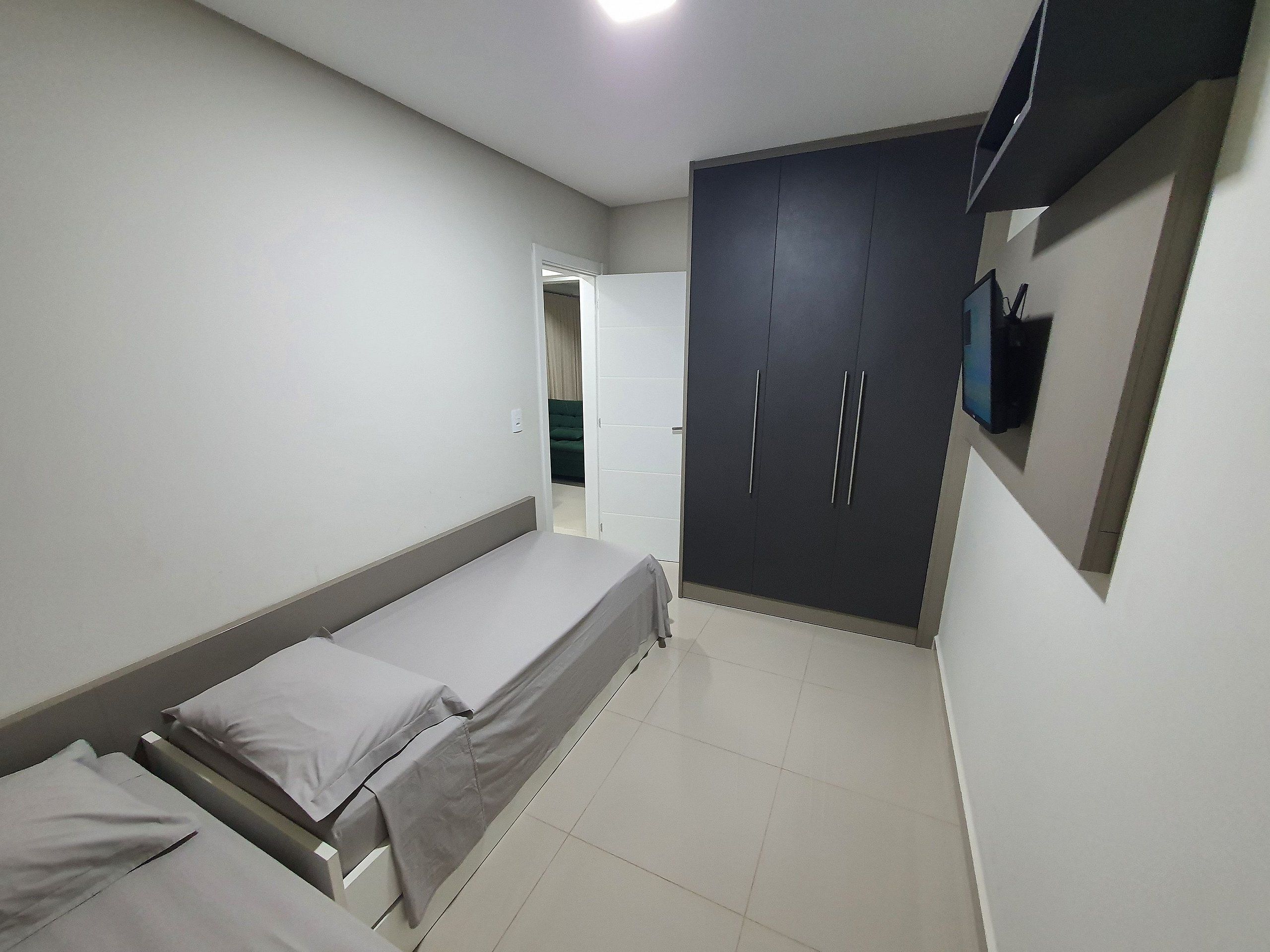 A bedroom with a bed, a wardrobe, and a television.