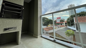 Una habitación con un ventanal grande con vistas a un paisaje urbano, una estantería metálica y una pared con textura.