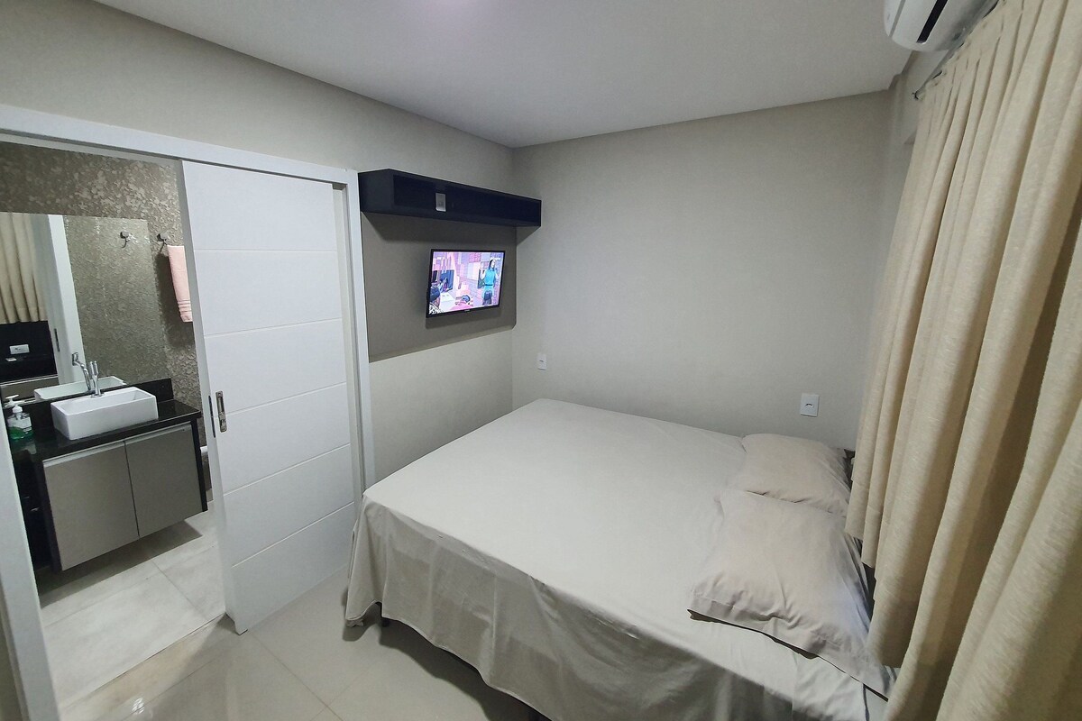 Ein Hotelzimmer mit einem Bett, einem an der Wand montierten Fernseher, einem Badezimmer mit einem Waschbecken und einem Kleiderschrank.