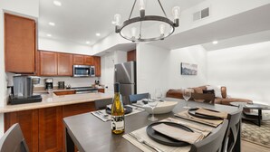 A modern kitchen with a central island, stainless steel appliances, and a dining area set for a meal.