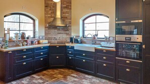 A modern kitchen with dark cabinetry, a central island, and a brick accent wall. - Nice home in Ljungbyhed with kitchen (Ljungbyhed)