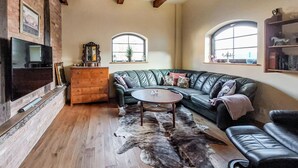 A cozy living room with a green leather sofa, a wooden coffee table, a TV mounted on a brick wall, and a fireplace. - Nice home in Ljungbyhed with kitchen (Ljungbyhed)