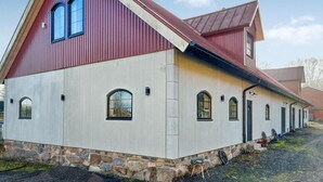 A red barn with a white lower section, stone foundation, and multiple windows. - Nice home in Ljungbyhed with kitchen (Ljungbyhed)