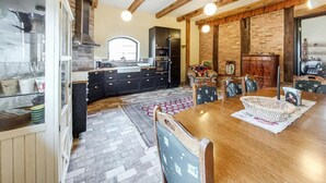 A spacious kitchen with a large island, wooden beams, and a dining area with a wooden table and chairs. - Nice home in Ljungbyhed with kitchen (Ljungbyhed)