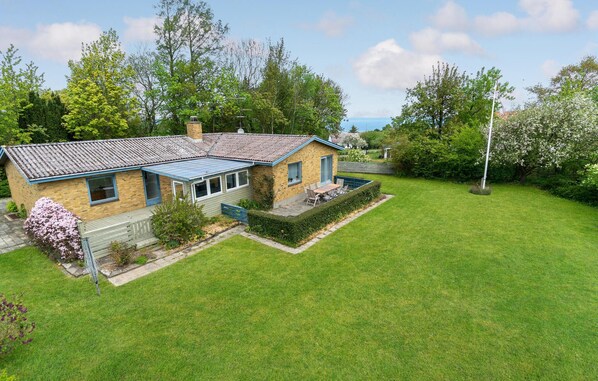 Set amidst a lush lawn and trees, this single-story house features a charming conservatory and a sloping roof.
