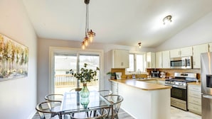 Una cocina moderna con armarios blancos, electrodomésticos de acero inoxidable y una mesa de comedor de vidrio.