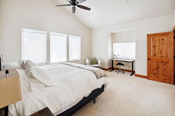 A bedroom with a bed, a desk, a chair, and a wooden door.