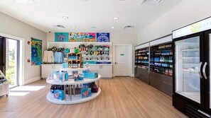 A clean, well-lit store with a central display of travel books and a refrigerated beverage case on the right.