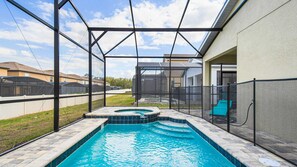 A backyard with a swimming pool, a hot tub, and a covered patio area.