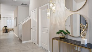 Un pasillo con una escalera, una consola decorativa y dos espejos en la pared.