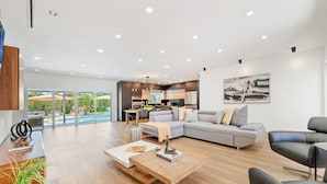 A modern living room with a sectional sofa, a coffee table, and a dining area with a table and chairs.