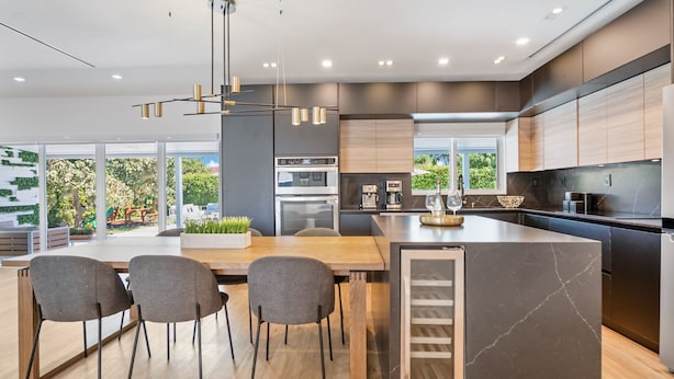 A modern kitchen with a large island, built-in appliances, and a view of greenery outside.